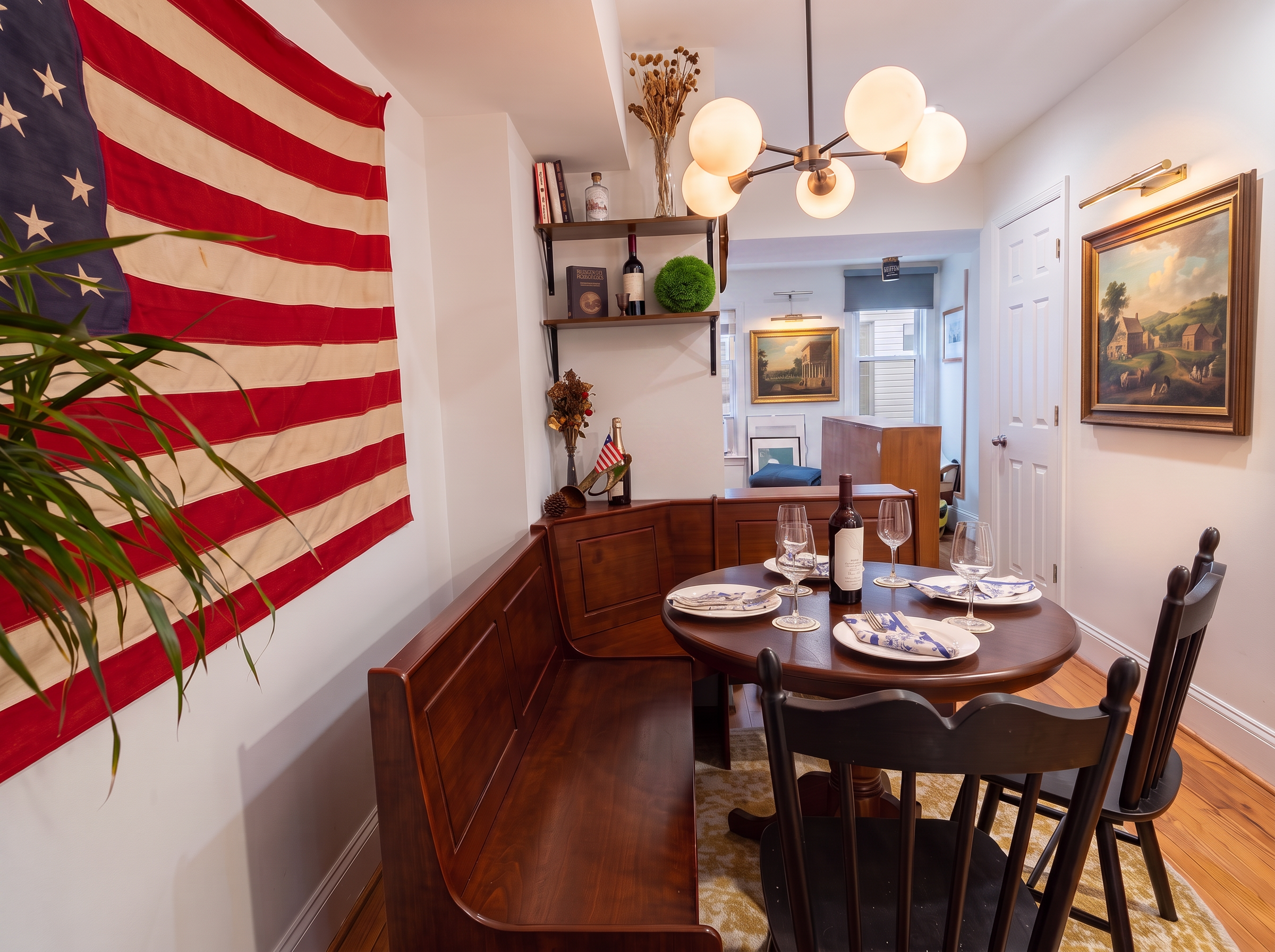 Front parlor with colonial artwork, illuminated picture lights and dining table